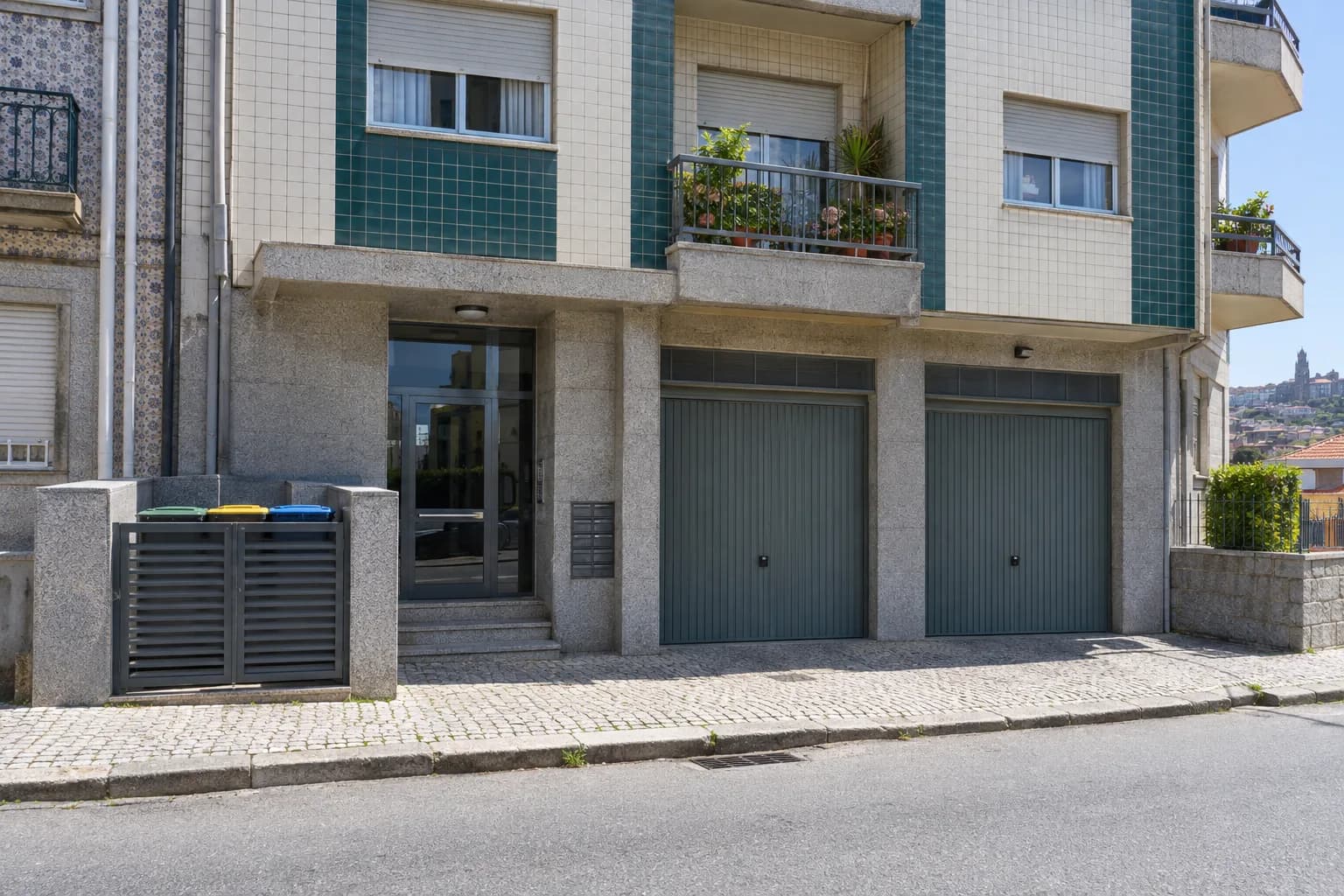Entrada e garagens de um prédio de apartamentos de granito e azulejo numa rua do Porto
